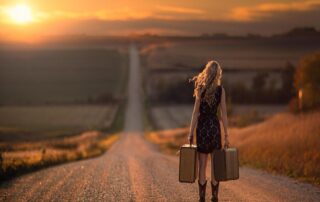 Woman walking into the distance at sunset, symbolizing the journey of manifesting a dream into reality.