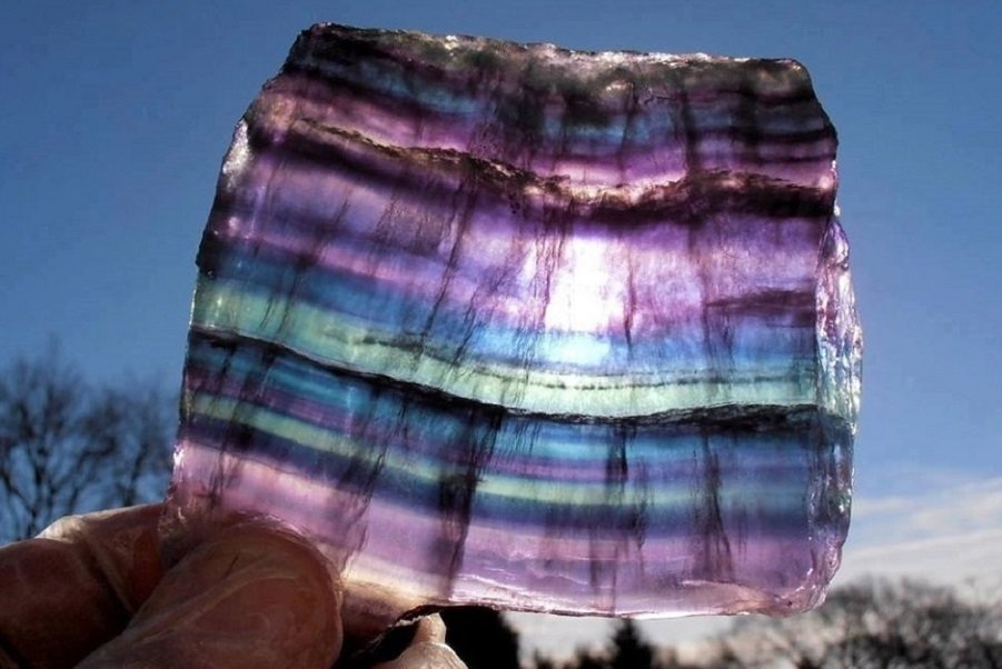 Long distance crystal healing with rainbow fluorite gemstone held in sunlight