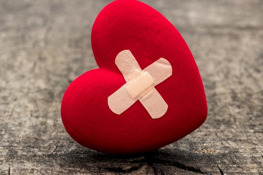 Red heart with bandages symbolizing healing emotional wounds and restoring emotional balance. - Help Recovering From Emotional Distress or Trauma