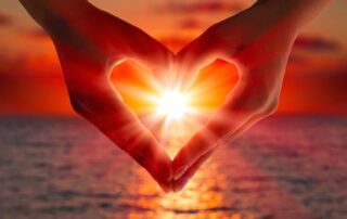Empathy run amuck - hands forming a heart shape around sunlight at the ocean