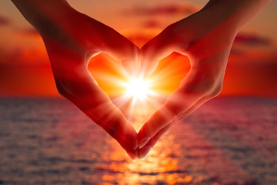 Empathy run amuck - hands forming a heart shape around sunlight at the ocean