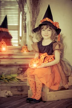 Lilly in Halloween witch costume with pumpkin lantern, symbolizing masks, identity, and playful self-expression