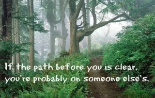 Forest trail with inspirational quote about finding your own path instead of following others.