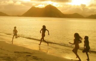 Children playing on the beach at sunset symbolizing our lives, our voices, and authentic self-expression.