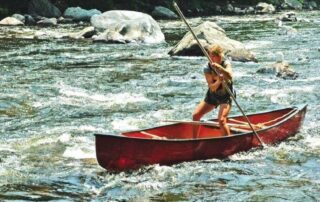Woman paddling a red canoe upstream symbolizing courage and determination in making tough life decisions.