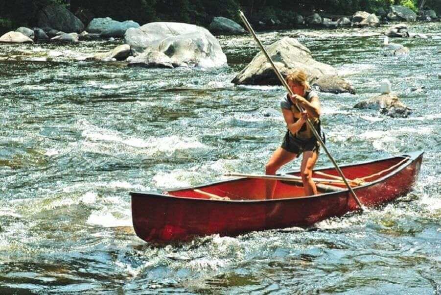 Woman paddling a red canoe upstream symbolizing courage and determination in making tough life decisions.