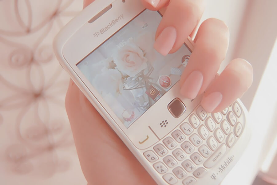 Soft pink-toned image of a woman’s hand holding a smartphone with a rose wallpaper, symbolizing sending a psychic SMS text psychic chat reading.