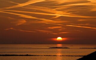 Sunset over calm water with golden clouds symbolizing peace, higher consciousness, and spiritual enlightenment