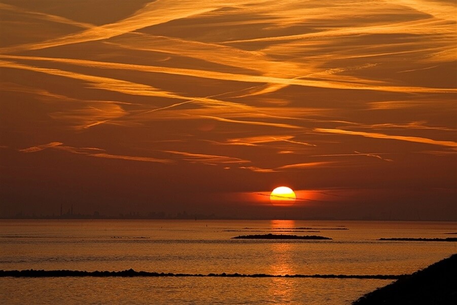 Sunset over calm water with golden clouds symbolizing peace, higher consciousness, and spiritual enlightenment