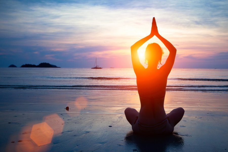 Woman meditating at sunrise on the beach – Spiritual Guidance with Psychic Lilly