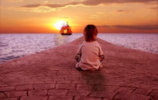 Child watching a distant ship at sunset – representing the urgency of living with intention