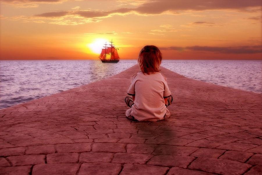 Child watching a distant ship at sunset – representing the urgency of living with intention