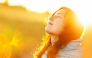 Woman basking in sunlight, symbolizing true happiness and inner peace.