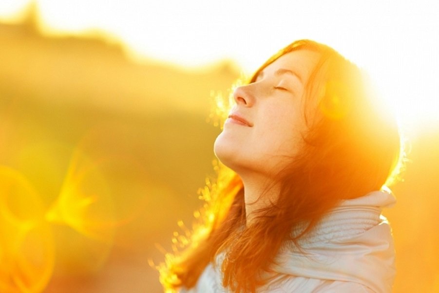 Woman basking in sunlight, symbolizing true happiness and inner peace.